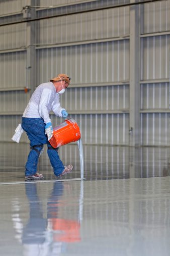 a construction worker pours epoxy on a flooring installation