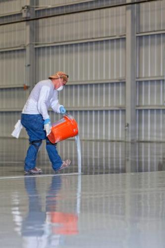 Construction Worker Pours Epoxy on a Floor